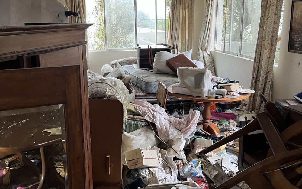 A living room piled with furniture and belongings before a full house clearance